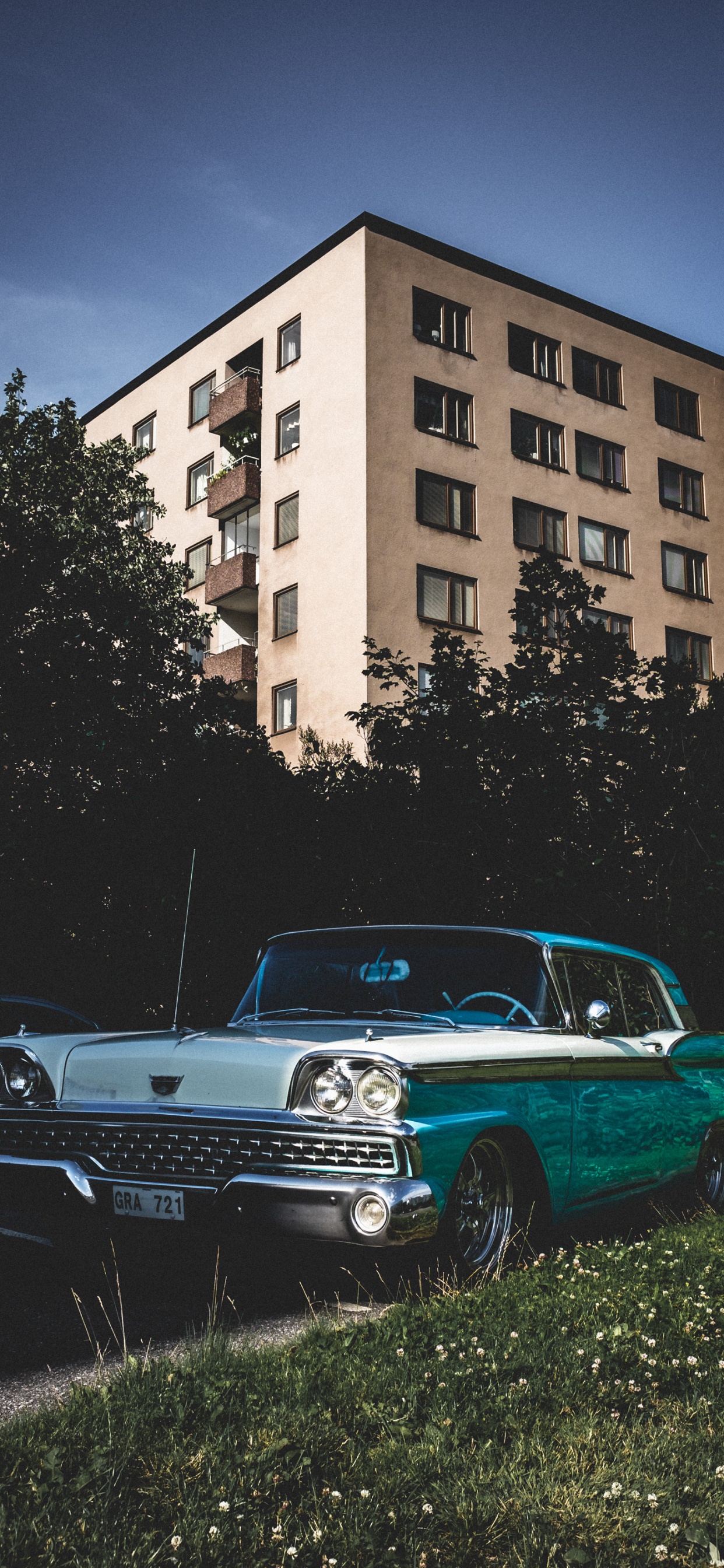 Blue Sedan Parked Beside Brown Concrete Building During Daytime. Wallpaper in 1242x2688 Resolution