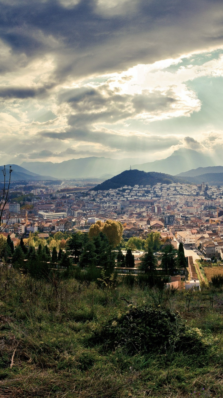 Green Grass Field Near City Buildings Under White Clouds and Blue Sky During Daytime. Wallpaper in 750x1334 Resolution