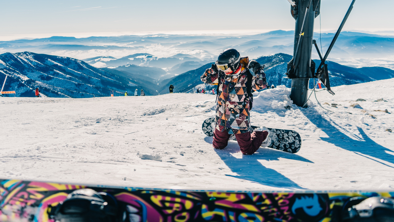 Hombre de Chaqueta Blanco y Negro Sentado en la Montaña Cubierta de Nieve Durante el Día. Wallpaper in 1280x720 Resolution
