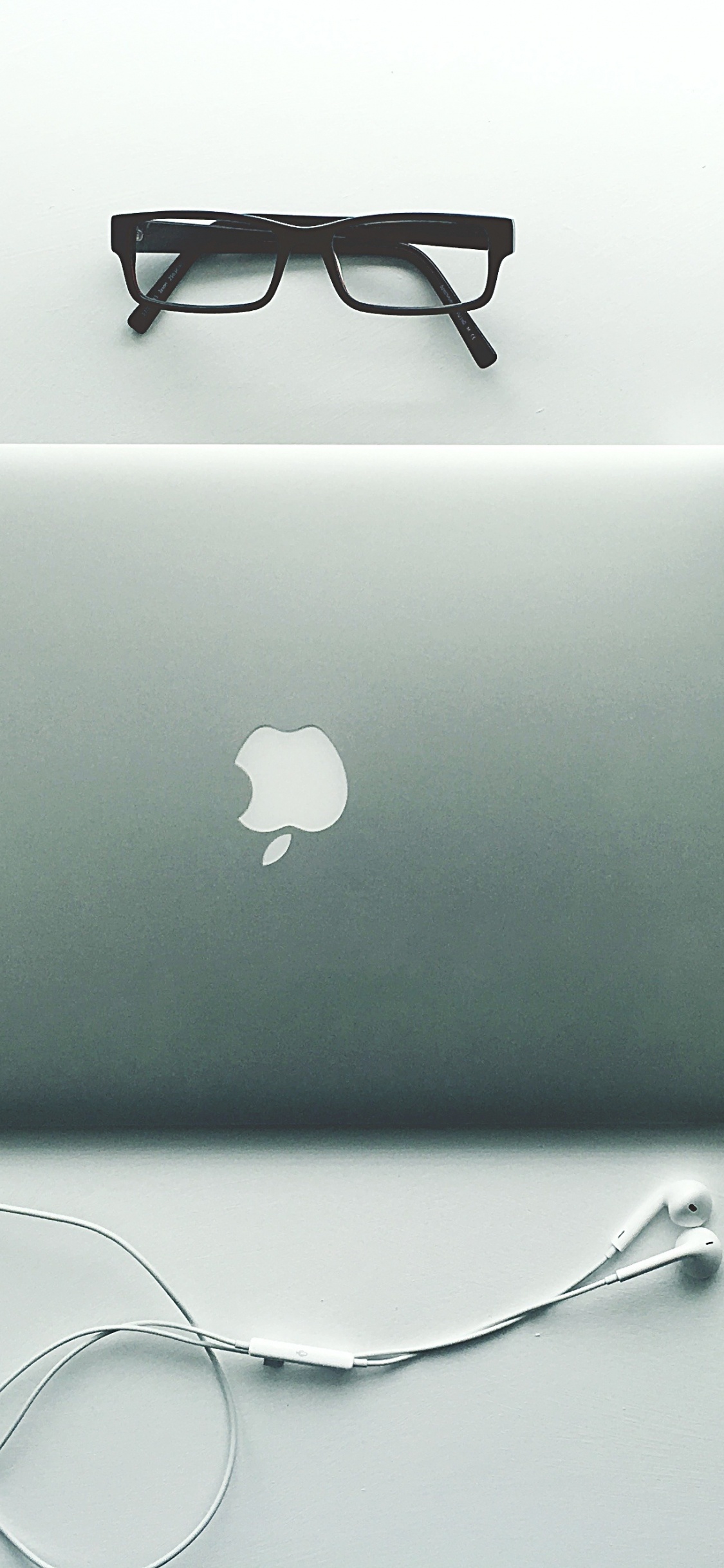 Silbernes MacBook Neben Schwarz Gerahmter Brille. Wallpaper in 1125x2436 Resolution