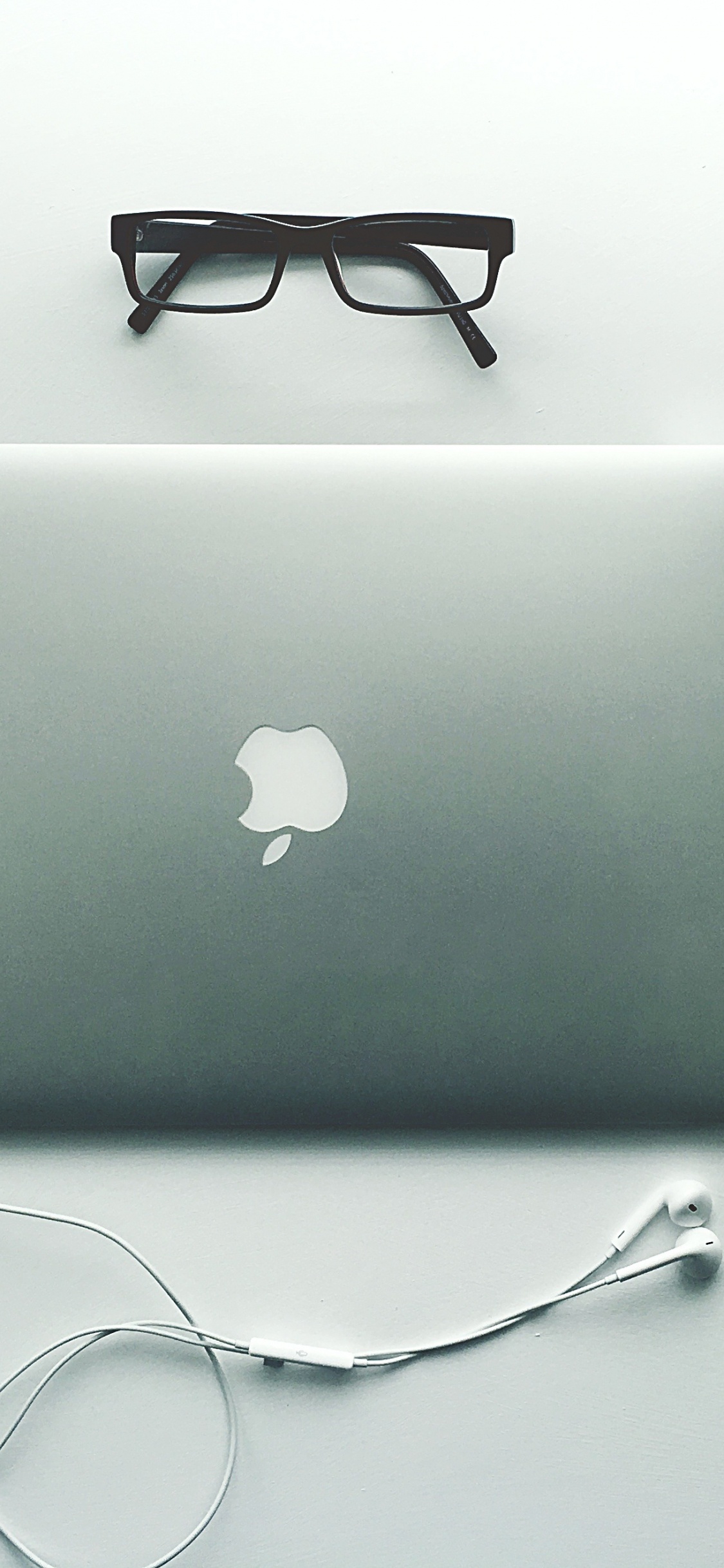 Macbook Argenté à Côté de Lunettes à Monture Noire. Wallpaper in 1125x2436 Resolution