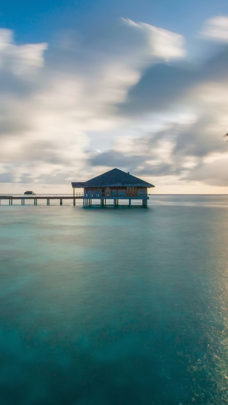 Braunes Holzhaus am Strand Unter Blauem Himmel Tagsüber. Wallpaper in 750x1334 Resolution