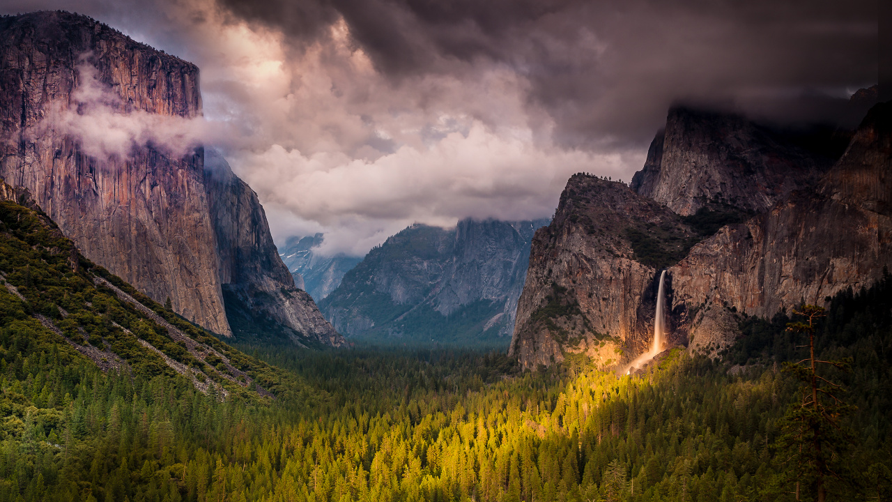 Green Grass Field Near Rocky Mountain Under Cloudy Sky. Wallpaper in 1280x720 Resolution