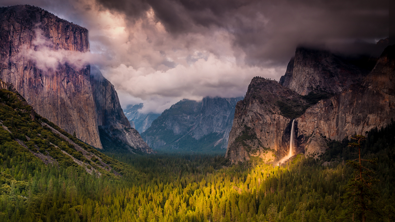 Green Grass Field Near Rocky Mountain Under Cloudy Sky. Wallpaper in 1366x768 Resolution