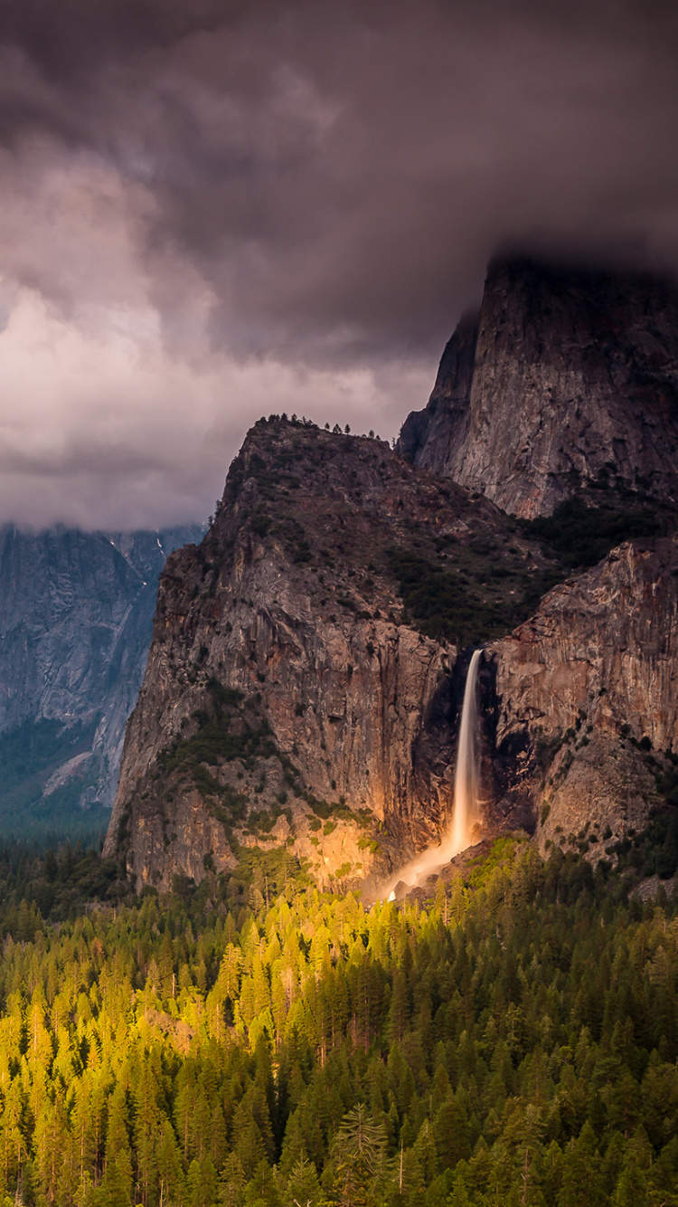 Green Grass Field Near Rocky Mountain Under Cloudy Sky. Wallpaper in 750x1334 Resolution