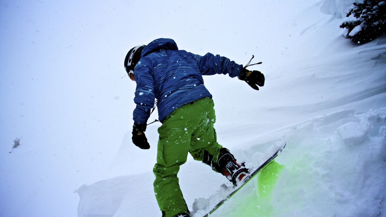Persona Con Chaqueta Azul y Pantalones Verdes Montados Sobre Palas de Esquí Sobre un Terreno Cubierto. Wallpaper in 1280x720 Resolution