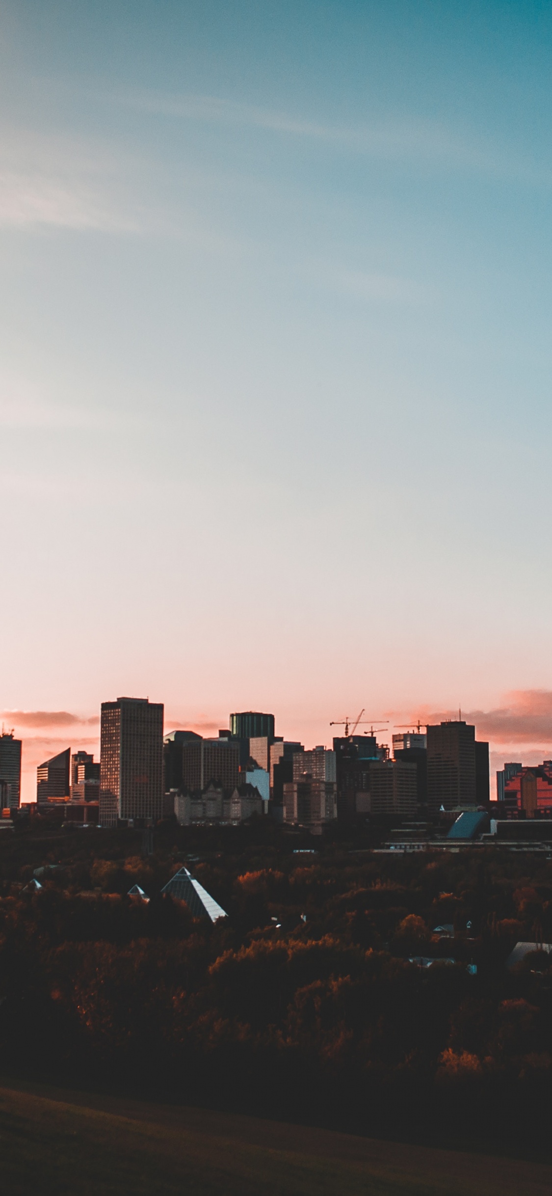 Skyline Der Stadt Unter Blauem Himmel Bei Sonnenuntergang. Wallpaper in 1125x2436 Resolution
