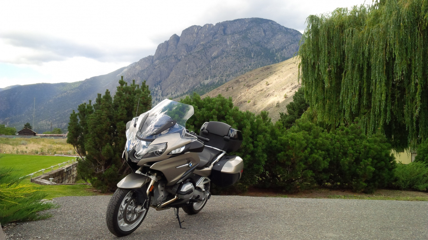 Black and Silver Motorcycle Parked on Brown Dirt Road Near Green Trees and Mountain During Daytime. Wallpaper in 1366x768 Resolution