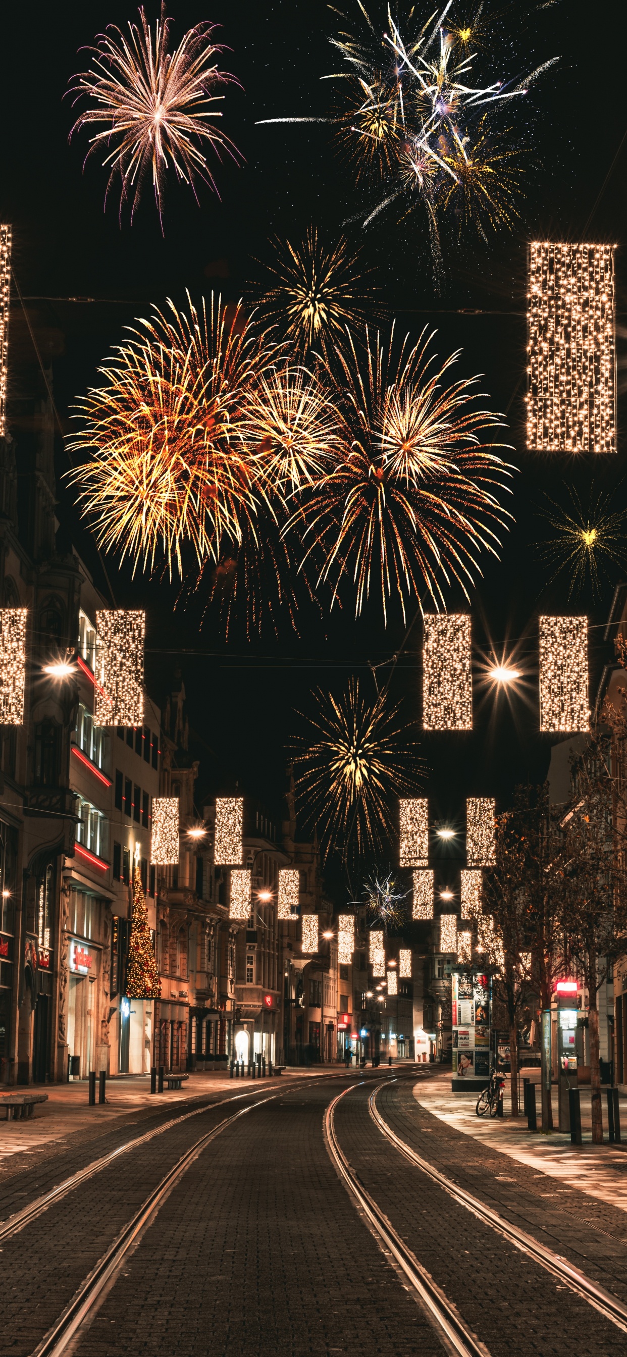 Leute, Die Nachts Auf Der Straße Mit Feuerwerk Gehen. Wallpaper in 1242x2688 Resolution