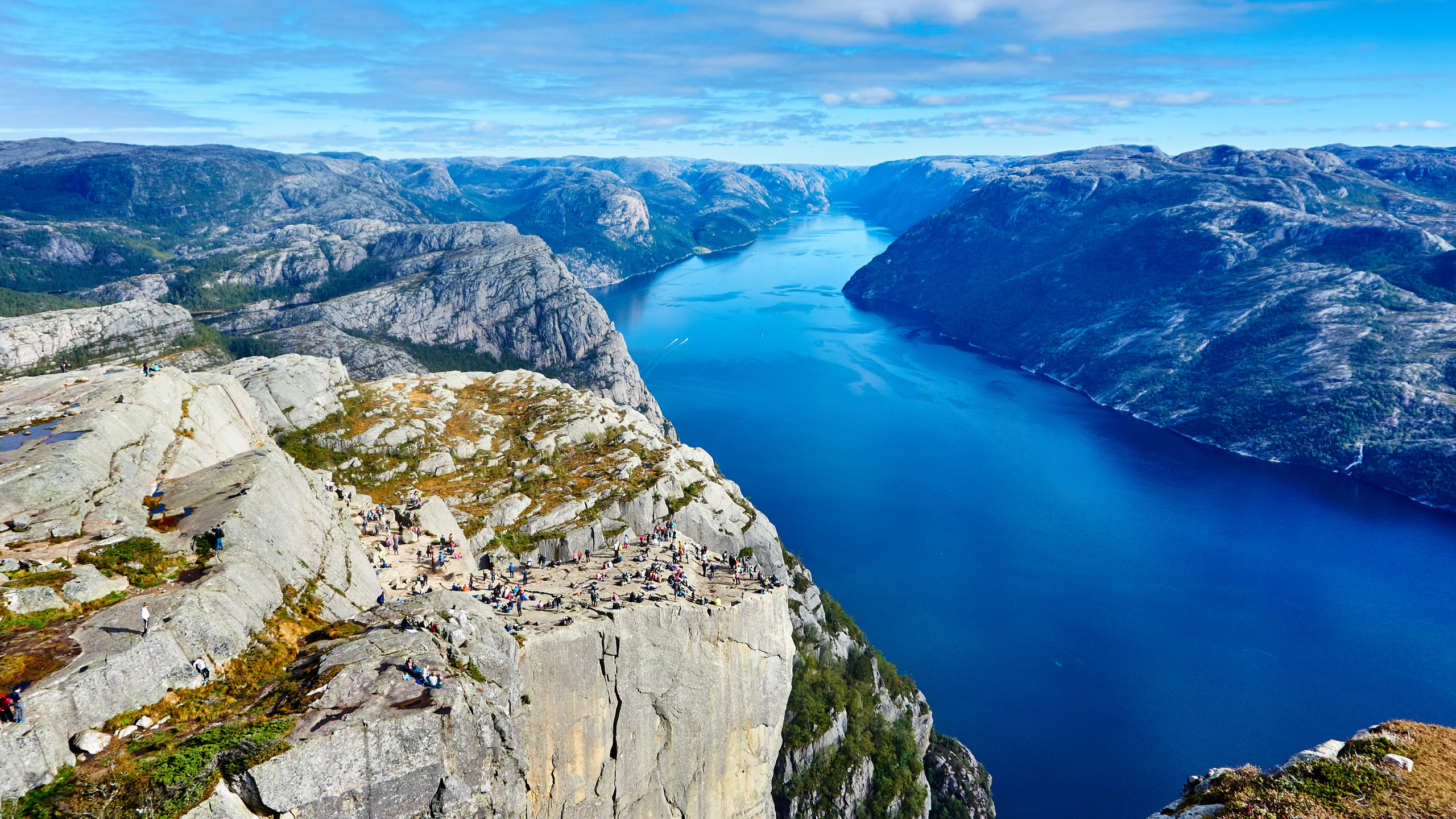 Blue Lake Between Gray Rocky Mountains Under Blue and White Sunny Cloudy Sky During Daytime. Wallpaper in 2560x1440 Resolution