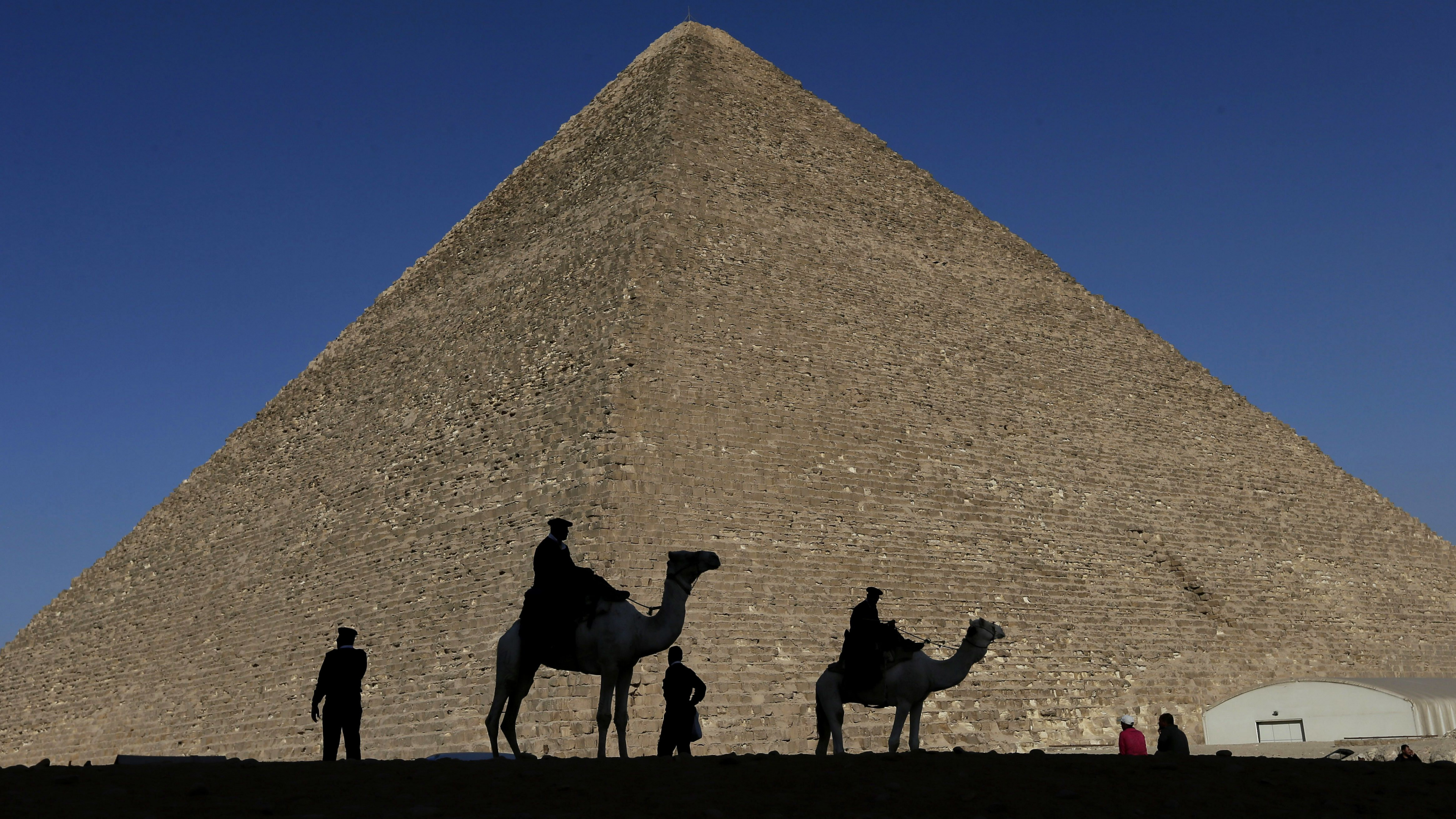 Group of People Riding Camels on Brown Sand Near Pyramid Under Blue Sky During Daytime. Wallpaper in 3840x2160 Resolution