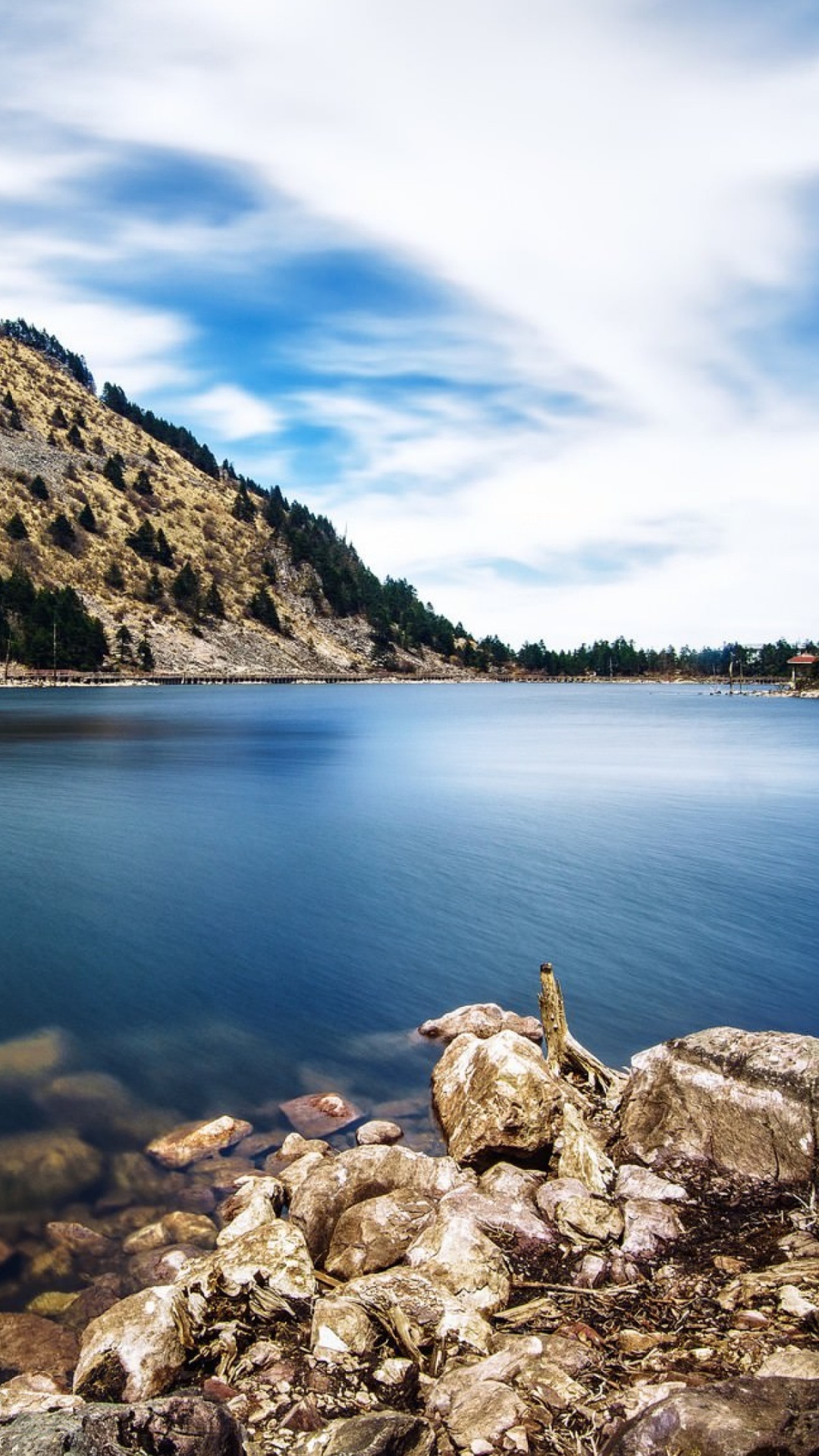 Person Sitting on Rock Near Body of Water During Daytime. Wallpaper in 1080x1920 Resolution