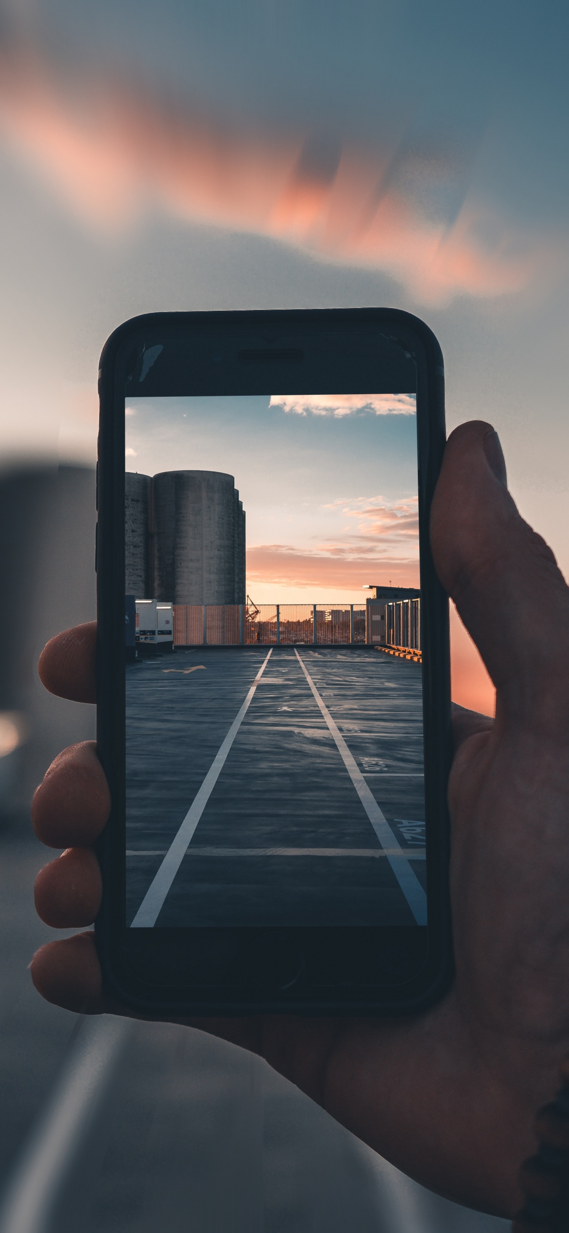 Person Holding Iphone Taking Photo of Sunset. Wallpaper in 1125x2436 Resolution