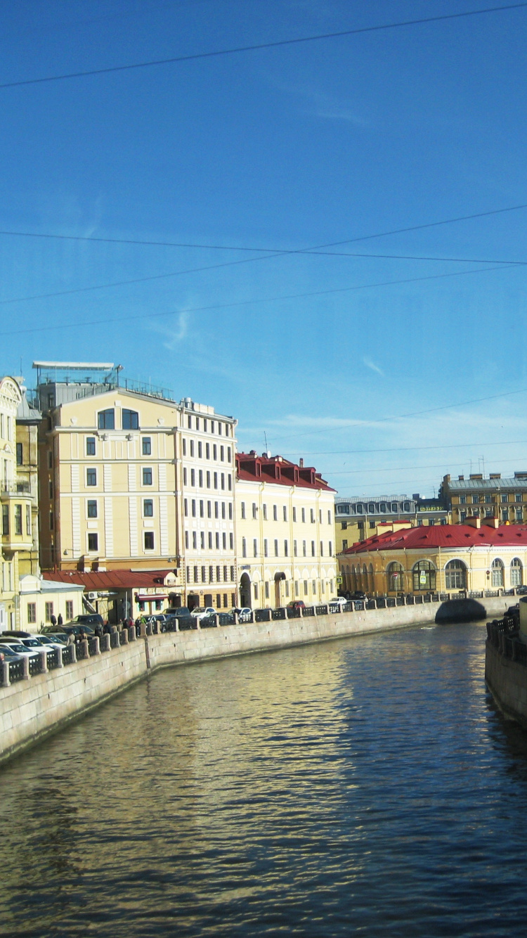 White and Brown Concrete Building Beside River Under Blue Sky During Daytime. Wallpaper in 750x1334 Resolution