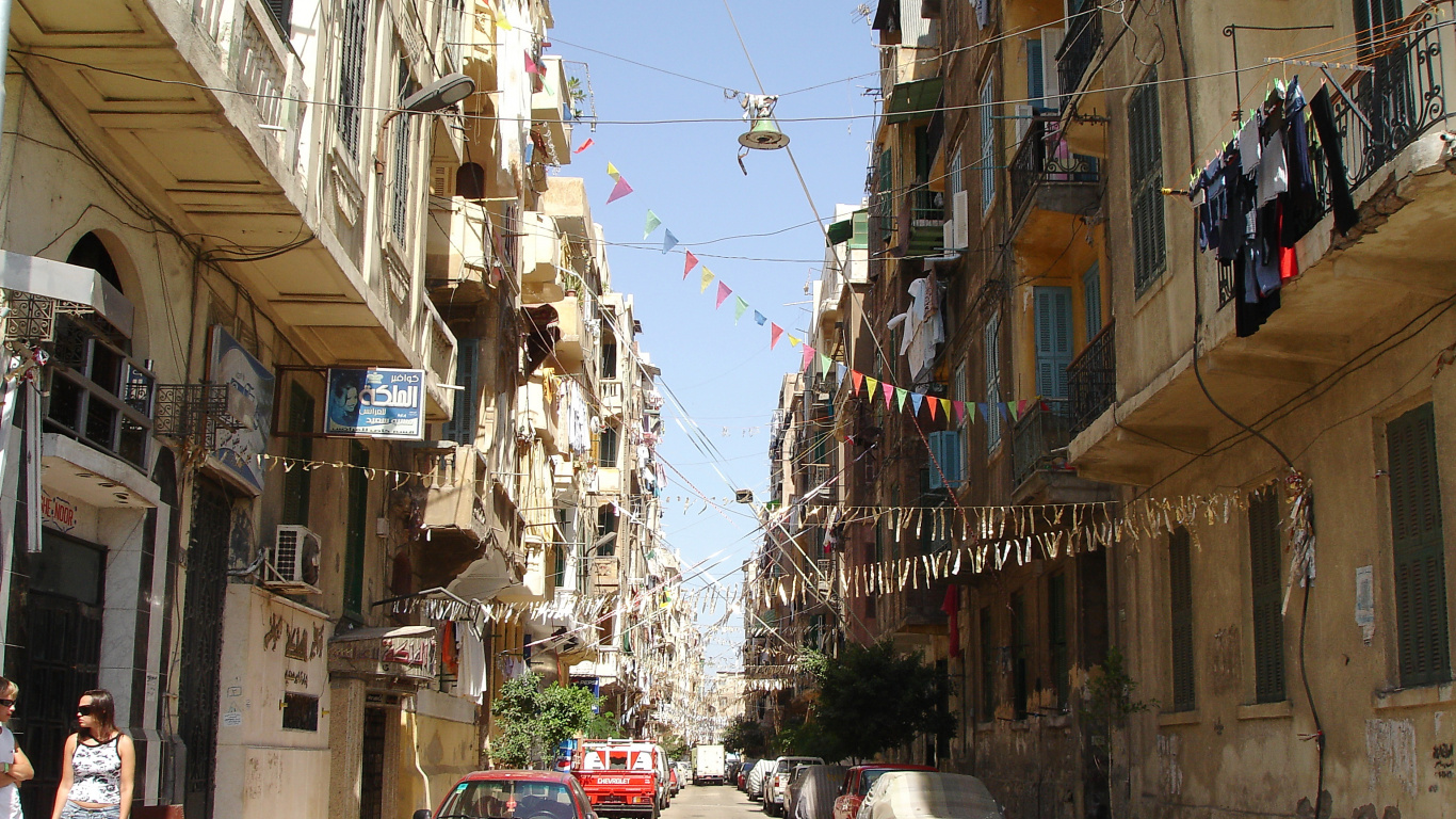 Coche Rojo Aparcado Junto al Edificio de Hormigón Gris Durante el Día. Wallpaper in 1366x768 Resolution