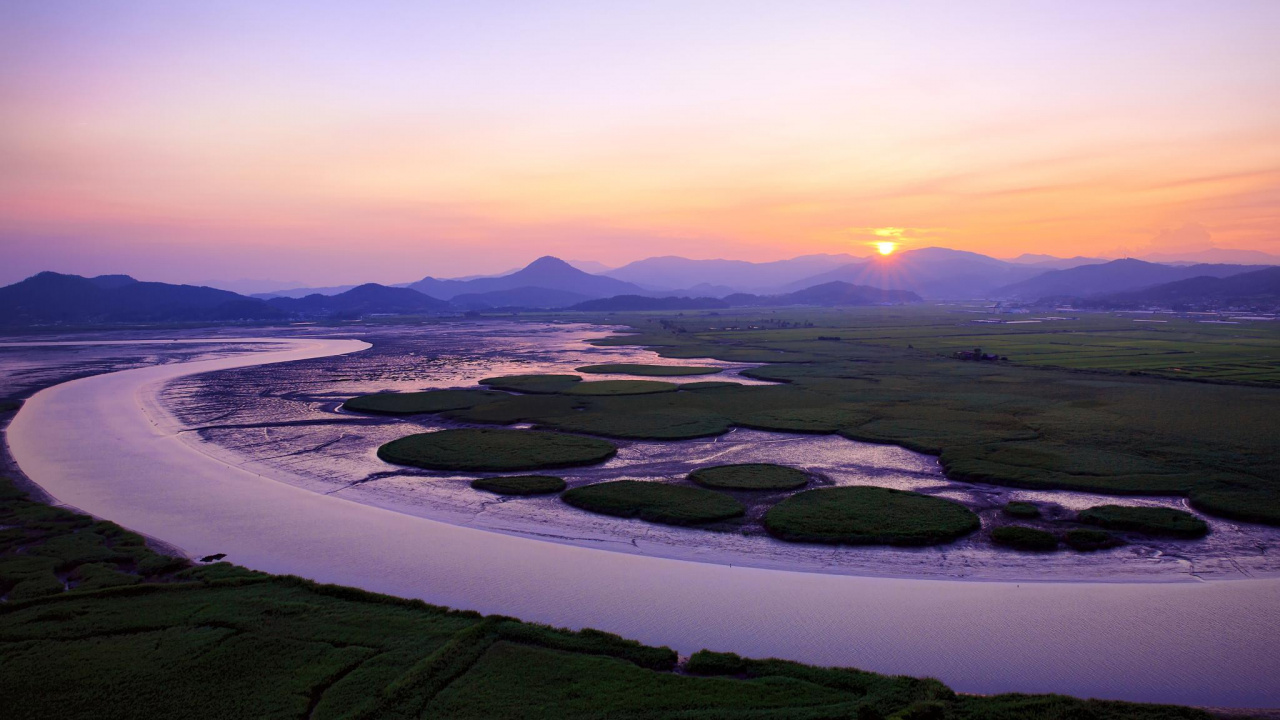 Green Grass Field Near Body of Water During Sunset. Wallpaper in 1280x720 Resolution