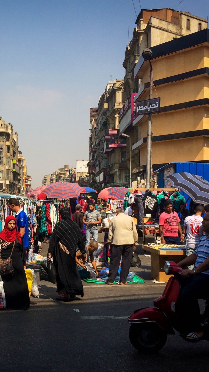 Personas en Una Calle Con Automóviles Estacionados a un Lado Durante el Día.. Wallpaper in 720x1280 Resolution