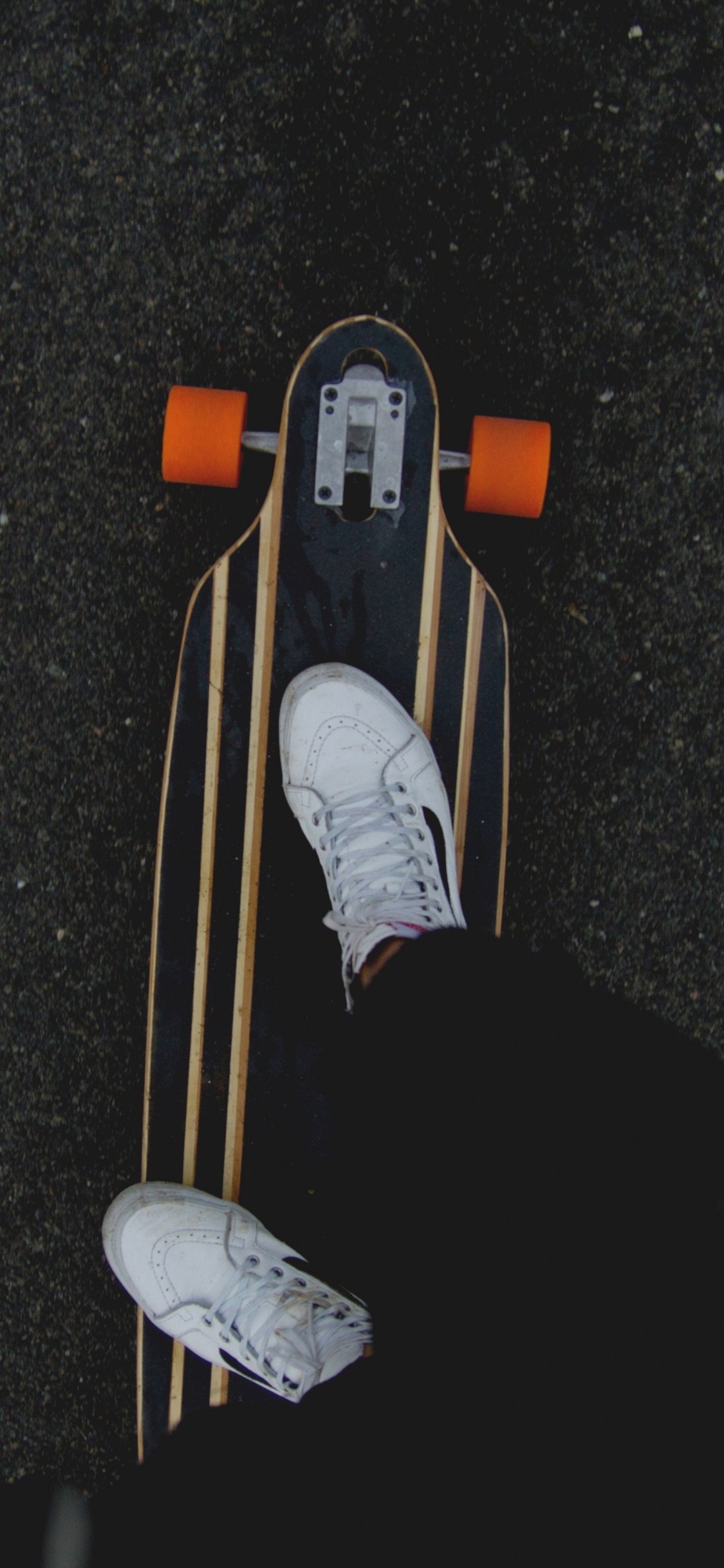 Person in Black Pants and White Sneakers Riding on Brown Wooden Skateboard. Wallpaper in 1125x2436 Resolution