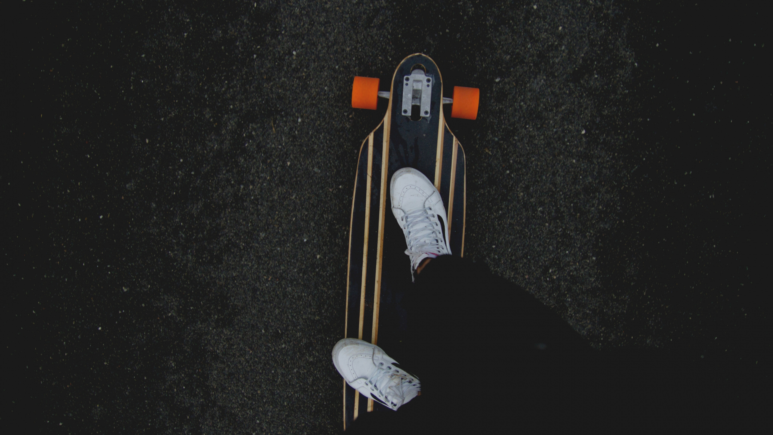 Person in Black Pants and White Sneakers Riding on Brown Wooden Skateboard. Wallpaper in 2560x1440 Resolution