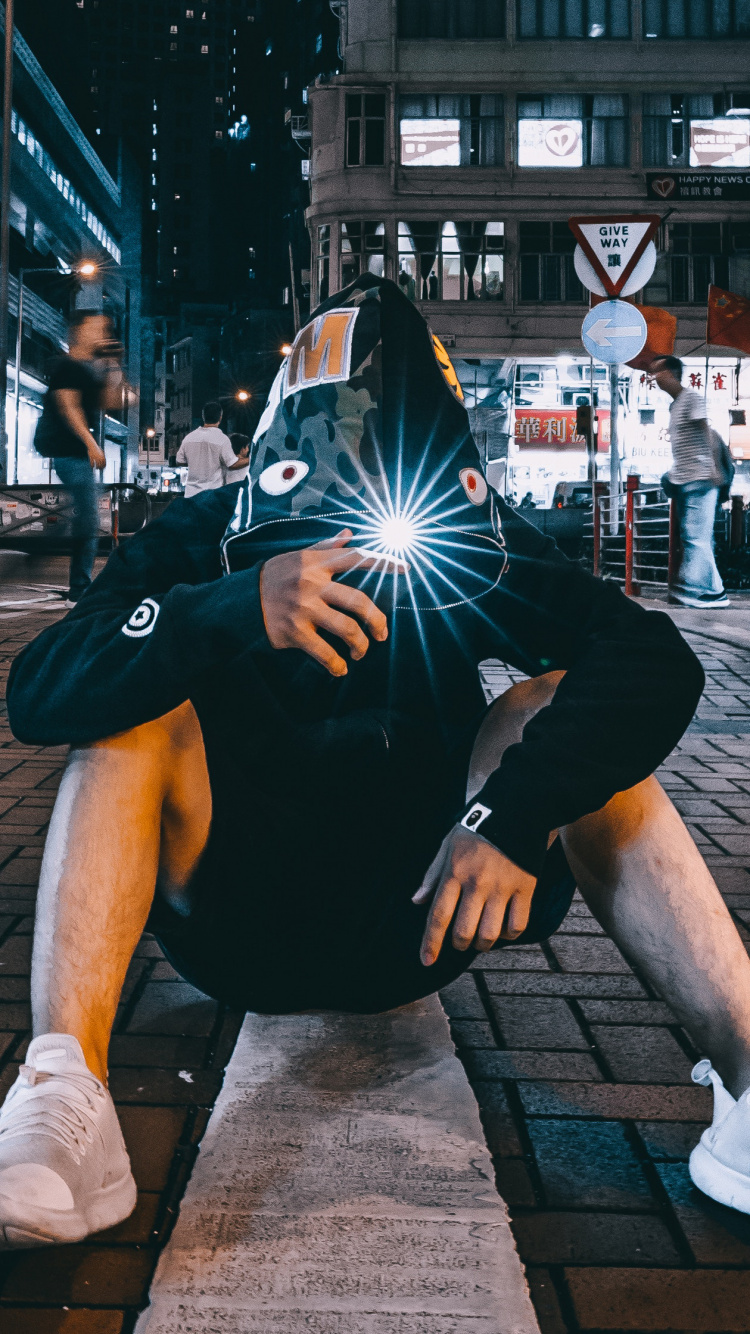 Mann im Schwarzen Und Weißen Nike-Rucksack, Der Tagsüber Auf Dem Bürgersteig Sitzt Sitting. Wallpaper in 750x1334 Resolution