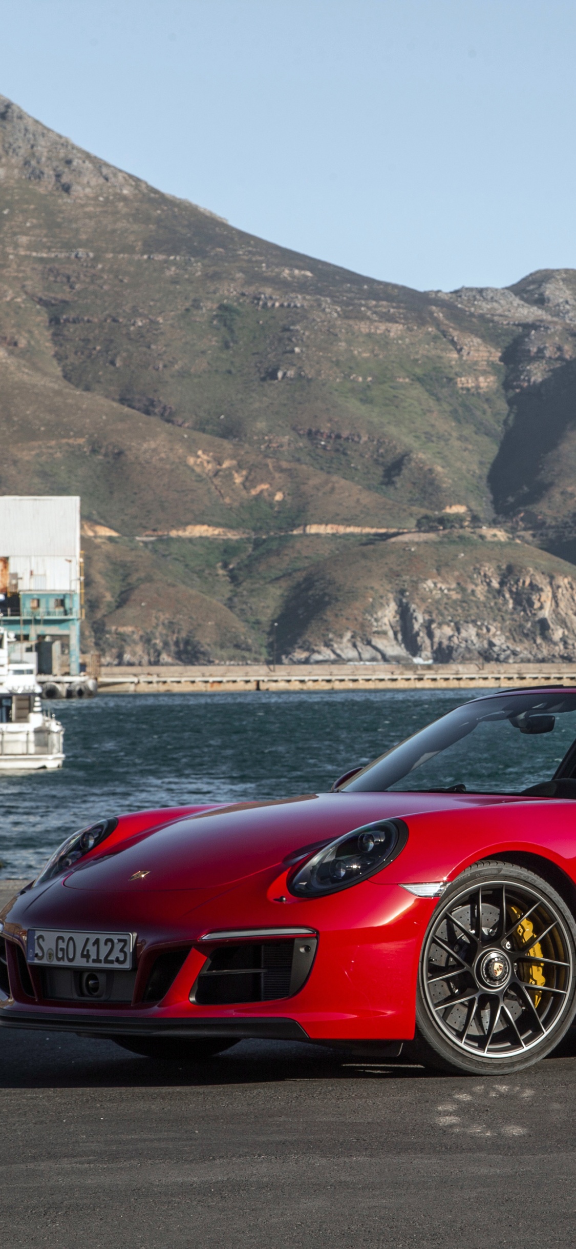 Roter Ferrari-Sportwagen am Strand Tagsüber. Wallpaper in 1125x2436 Resolution