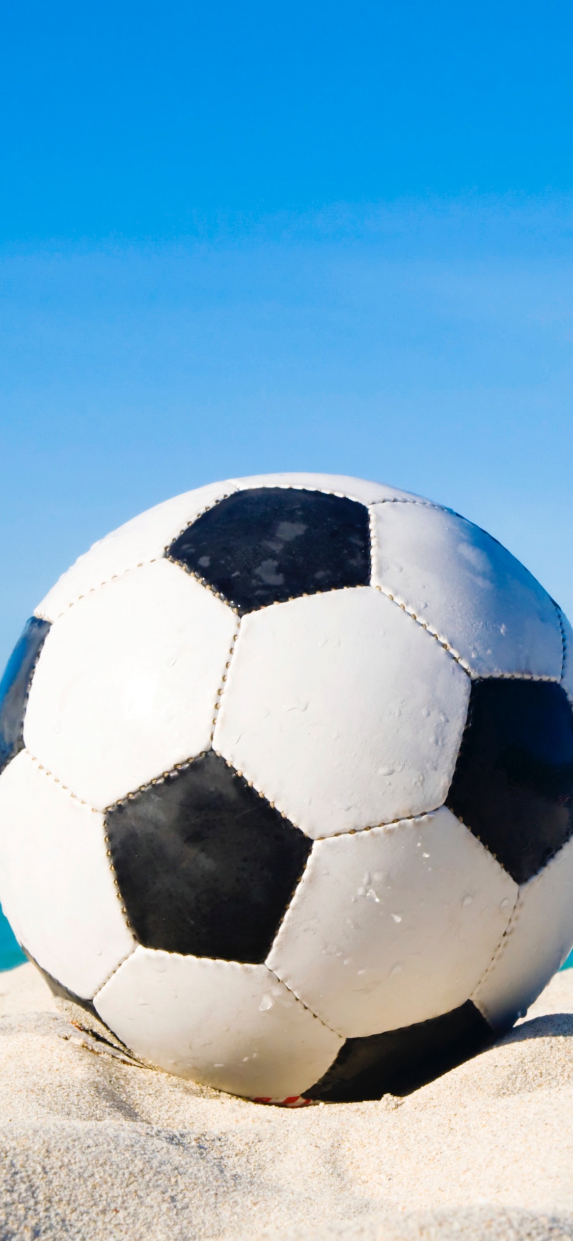 White and Black Soccer Ball on White Sand During Daytime. Wallpaper in 1125x2436 Resolution