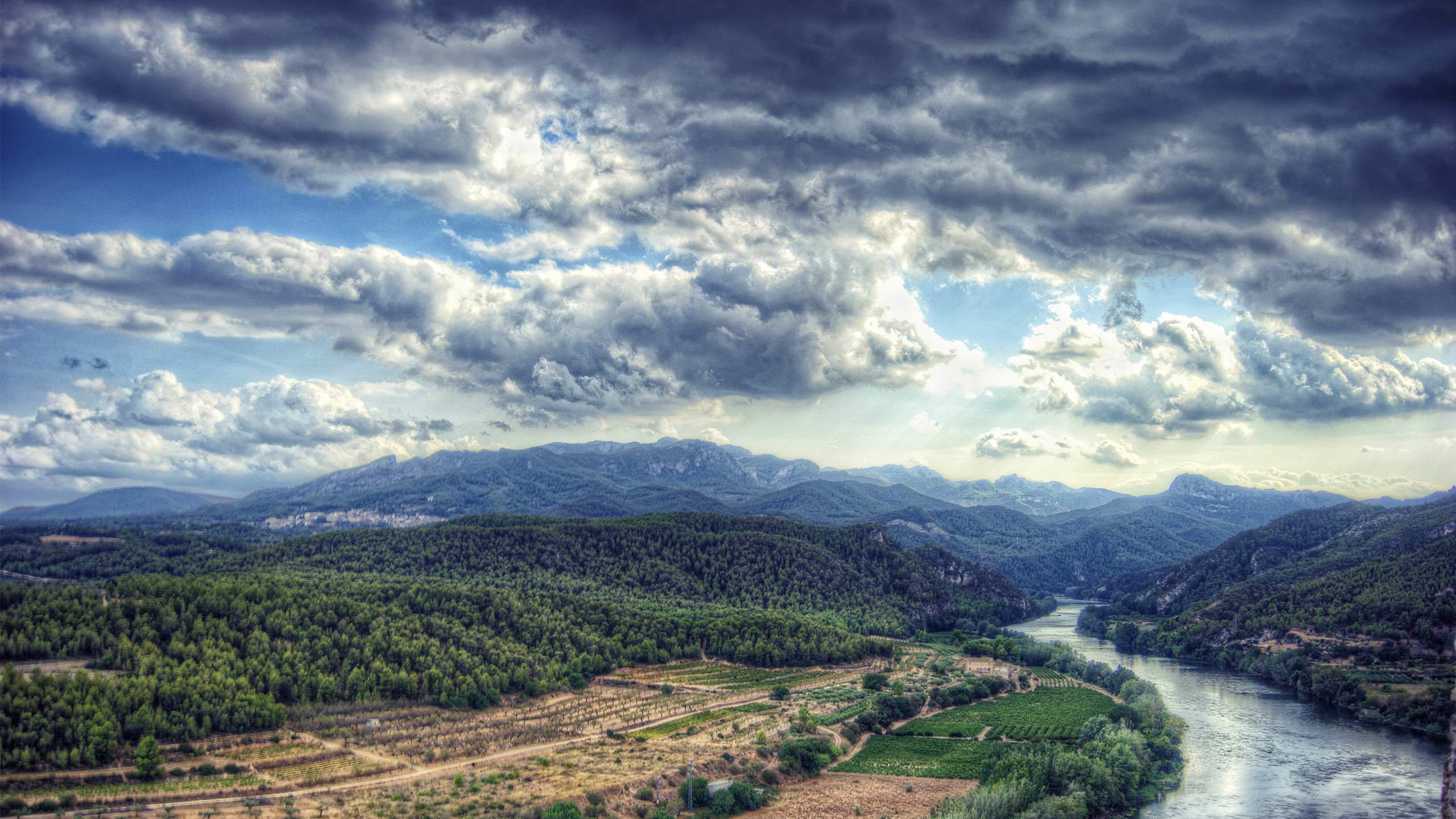 Campo de Hierba Verde Cerca de la Montaña Bajo Nubes Blancas Durante el Día. Wallpaper in 2560x1440 Resolution