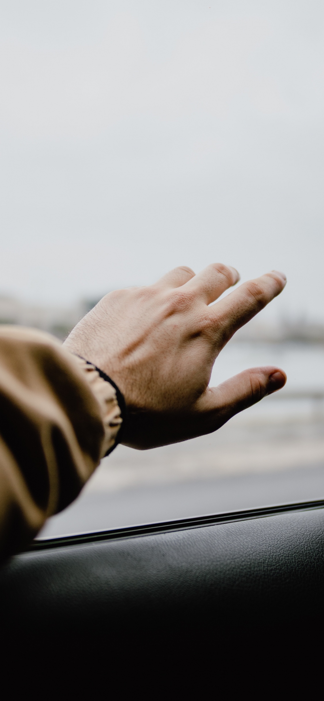 Person in Brauner Jacke Mit Autofenster. Wallpaper in 1125x2436 Resolution