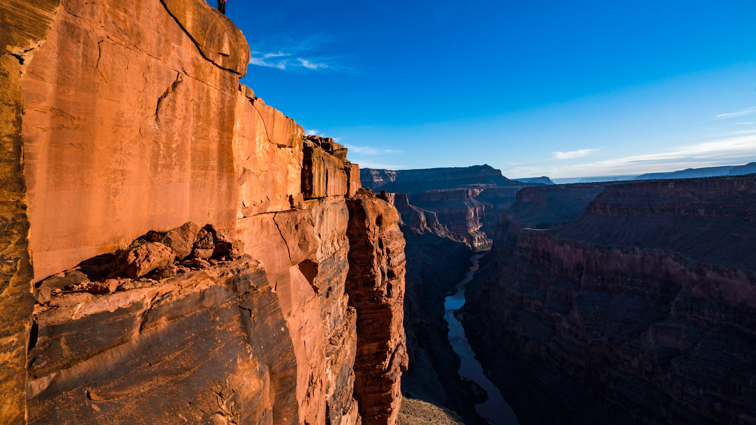 Person Standing on Brown Rock Formation During Daytime. Wallpaper in 2560x1440 Resolution