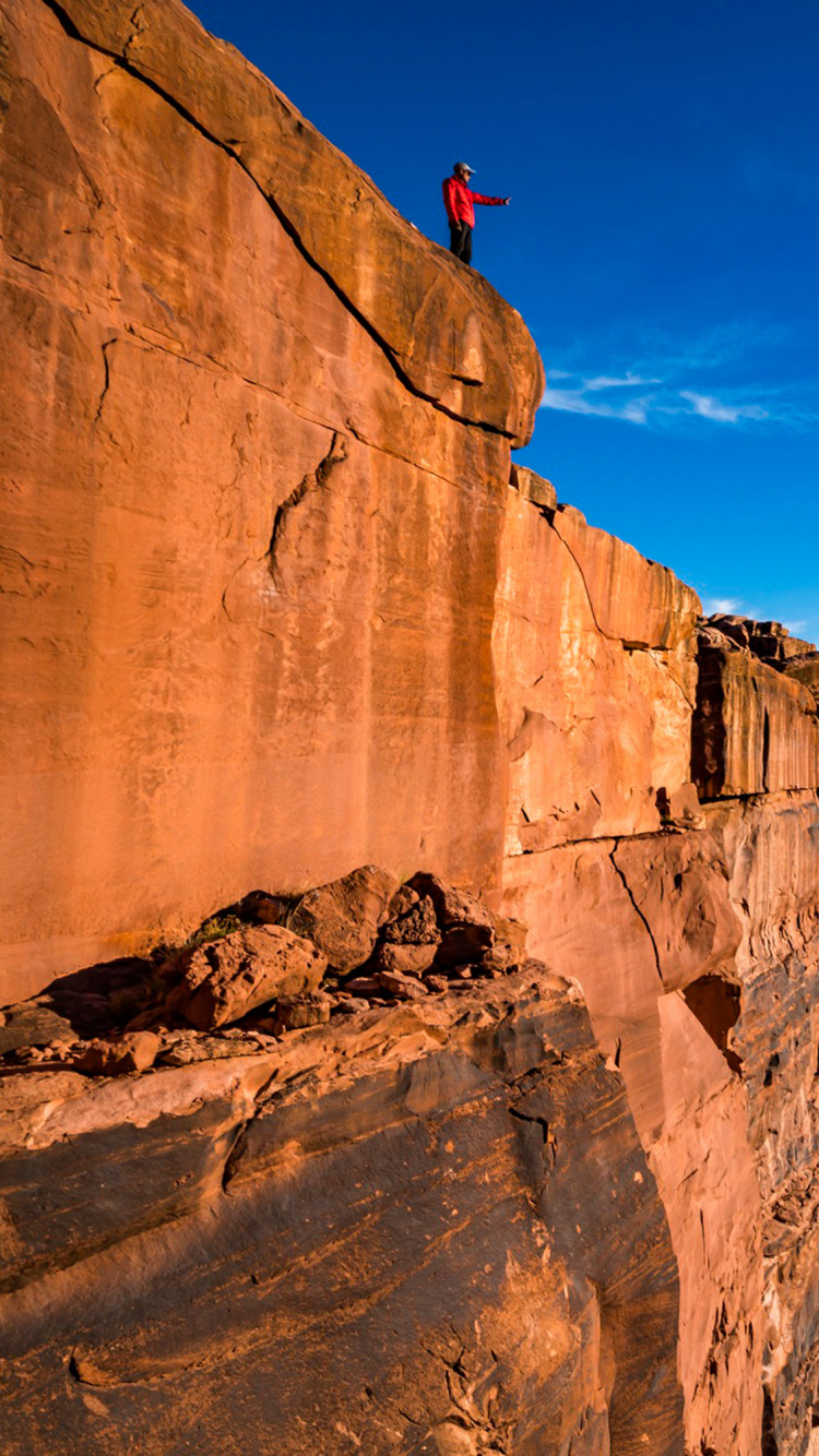 Person Standing on Brown Rock Formation During Daytime. Wallpaper in 750x1334 Resolution