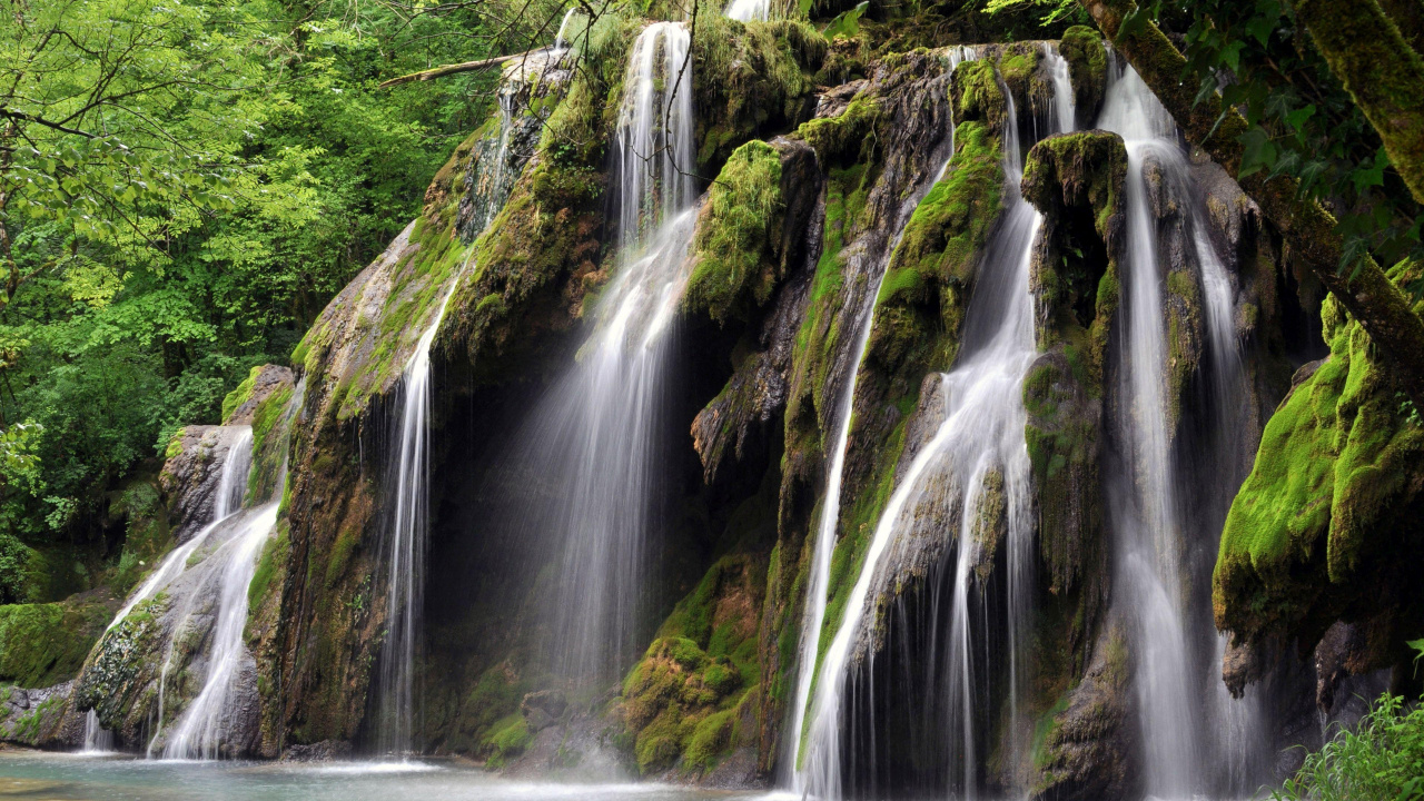 El Agua Cae en Medio de Rocas Cubiertas de Musgo Verde.. Wallpaper in 1280x720 Resolution