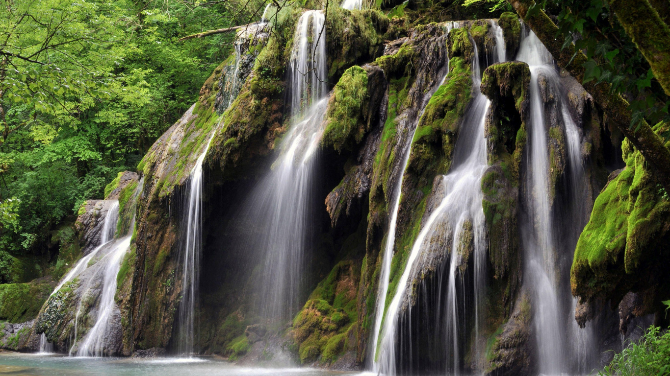 El Agua Cae en Medio de Rocas Cubiertas de Musgo Verde.. Wallpaper in 1366x768 Resolution