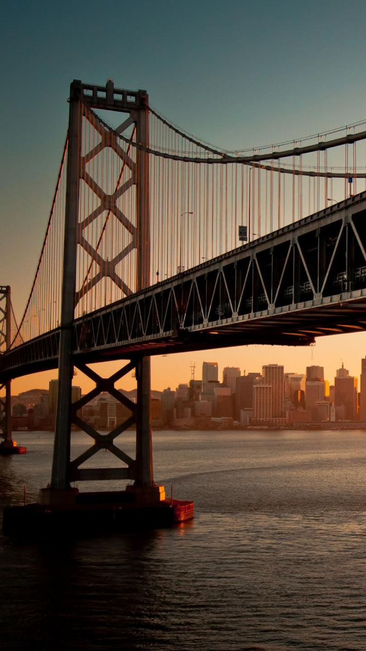 Black Bridge Over Body of Water During Sunset. Wallpaper in 750x1334 Resolution