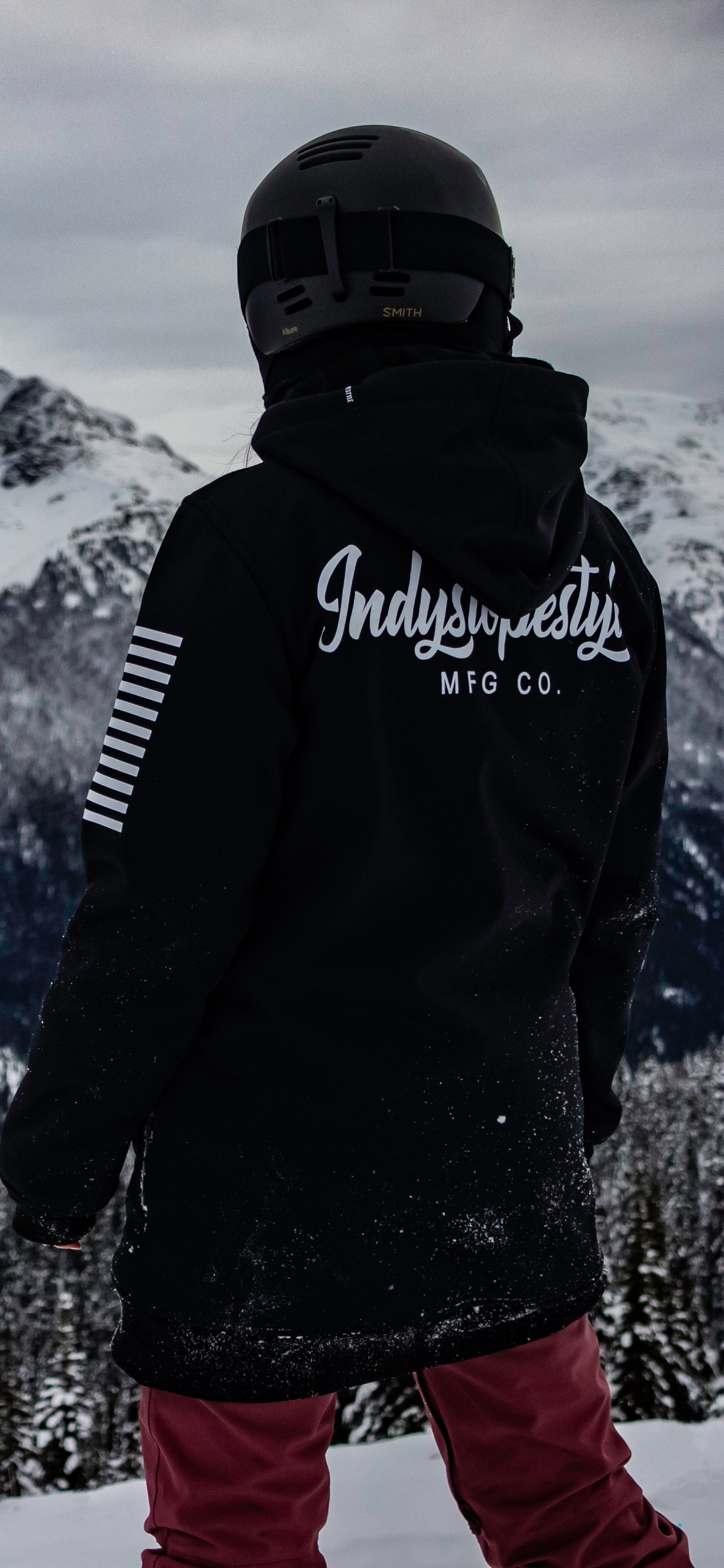 Man in Black Jacket and Red Pants Standing on Snow Covered Ground. Wallpaper in 1125x2436 Resolution