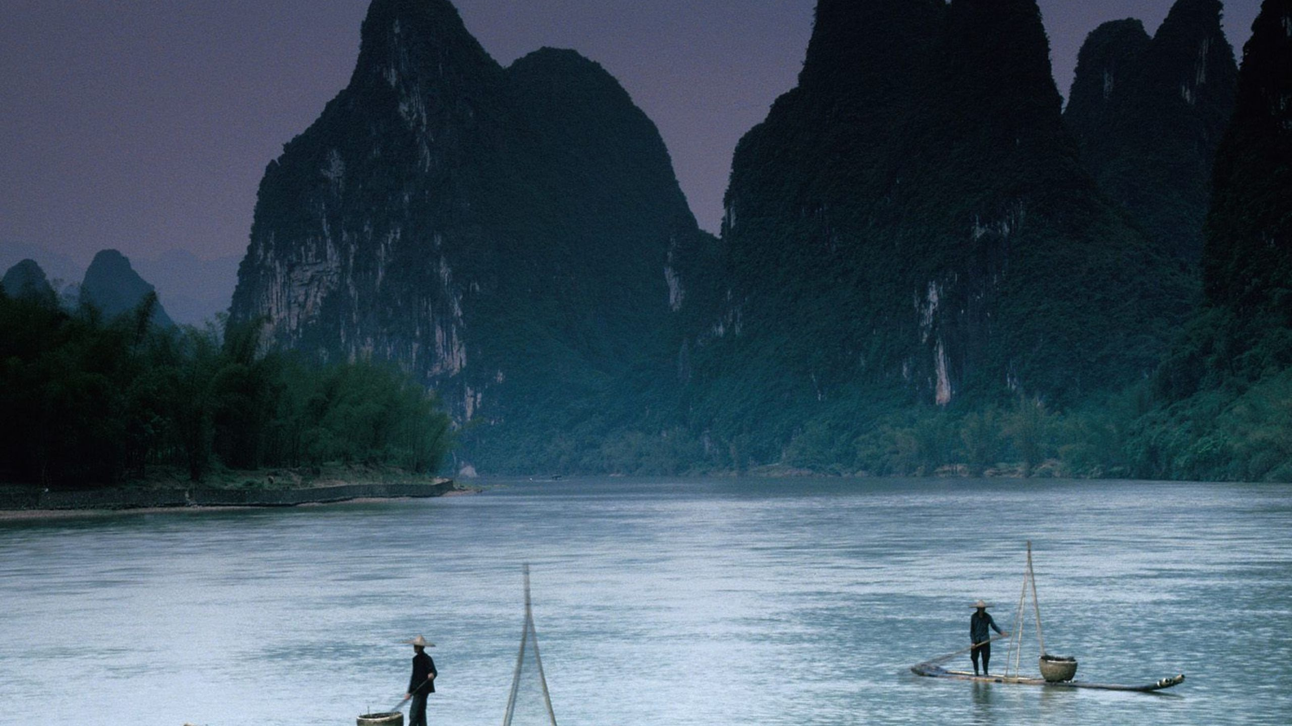 Man in Black Shirt and Black Shorts Standing on Boat on Sea During Daytime. Wallpaper in 2560x1440 Resolution