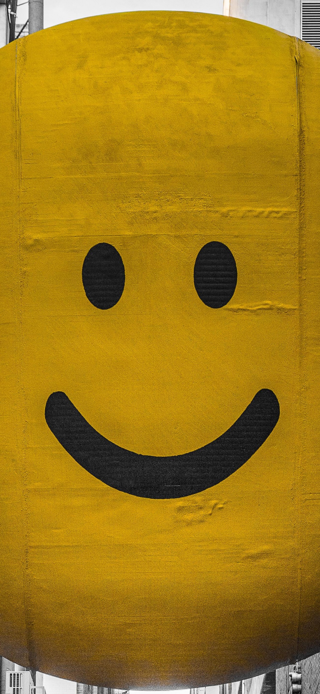 Globo Sonriente Amarillo Sobre Tabla de Madera Gris. Wallpaper in 1125x2436 Resolution