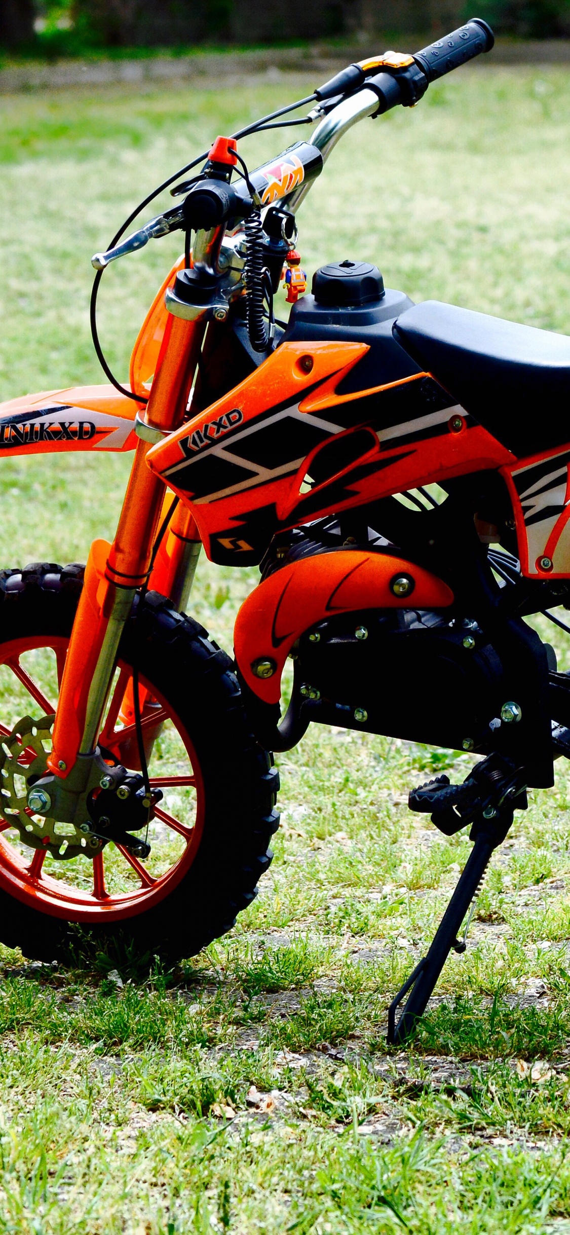 Orange and Black Sports Bike on Green Grass Field During Daytime. Wallpaper in 1125x2436 Resolution