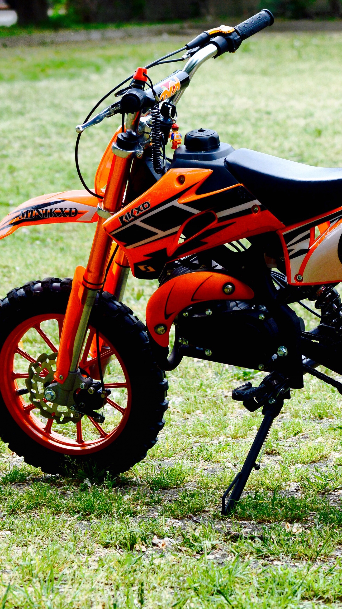 Orange Und Schwarzes Sportfahrrad Auf Grüner Wiese Tagsüber. Wallpaper in 1440x2560 Resolution