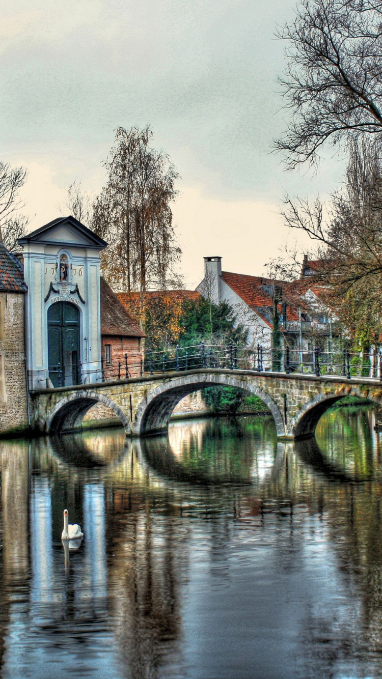 Brown Concrete Building Near Body of Water During Daytime. Wallpaper in 750x1334 Resolution