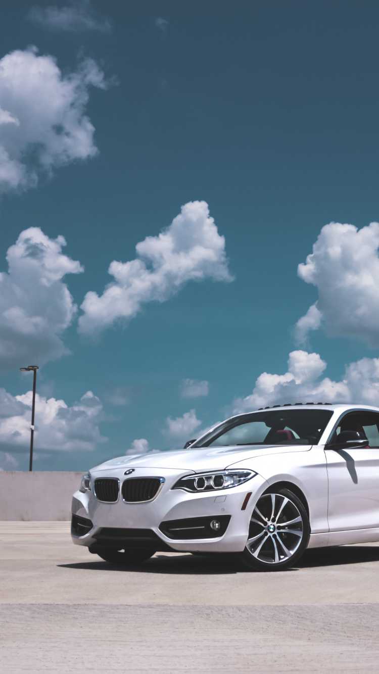 Coupé Bmw m 3 Blanc Sur Champ Brun Sous Ciel Nuageux Ensoleillé Bleu et Blanc Pendant. Wallpaper in 750x1334 Resolution