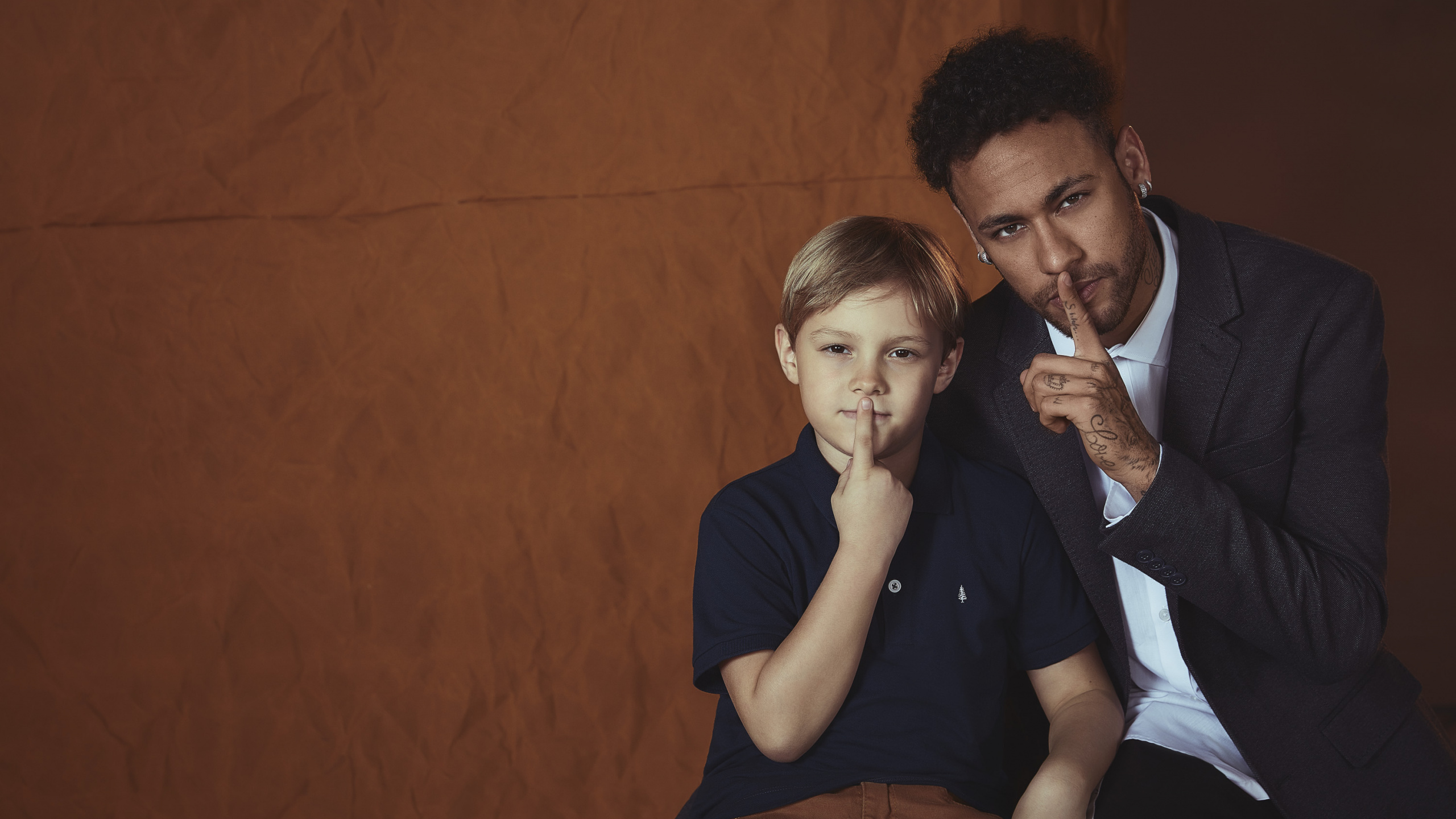 Mann im Schwarzen T-Shirt Mit Rundhalsausschnitt Sitzt Auf Schwarzem Stuhl. Wallpaper in 2560x1440 Resolution