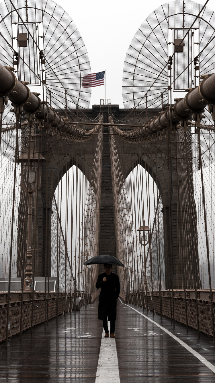 Woman in Black Jacket and Black Pants Walking on Bridge During Daytime. Wallpaper in 750x1334 Resolution
