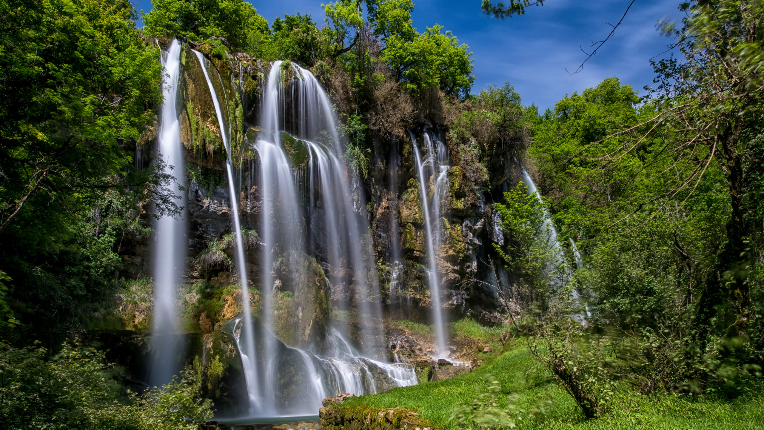 Cascades Sur Terrain D'herbe Verte Sous Ciel Bleu Pendant la Journée. Wallpaper in 2560x1440 Resolution
