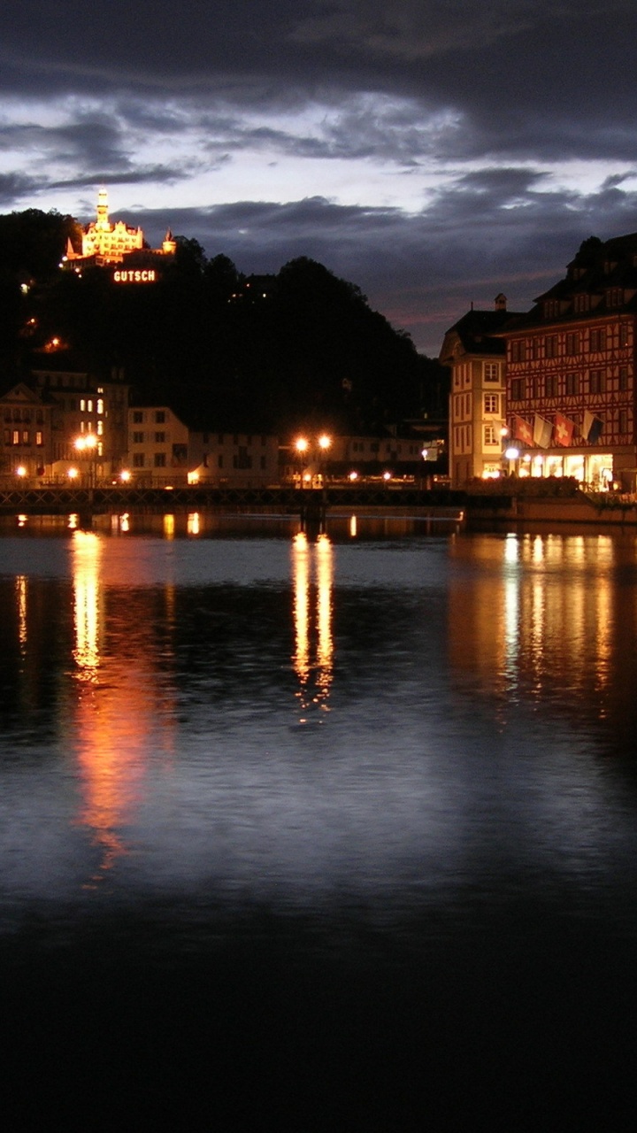 Braunes Betongebäude in Der Nähe Von Gewässern Während Der Nacht. Wallpaper in 720x1280 Resolution