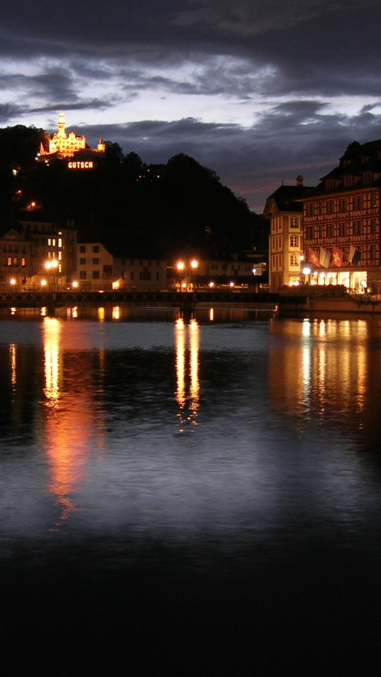 Brown Concrete Building Near Body of Water During Night Time. Wallpaper in 750x1334 Resolution
