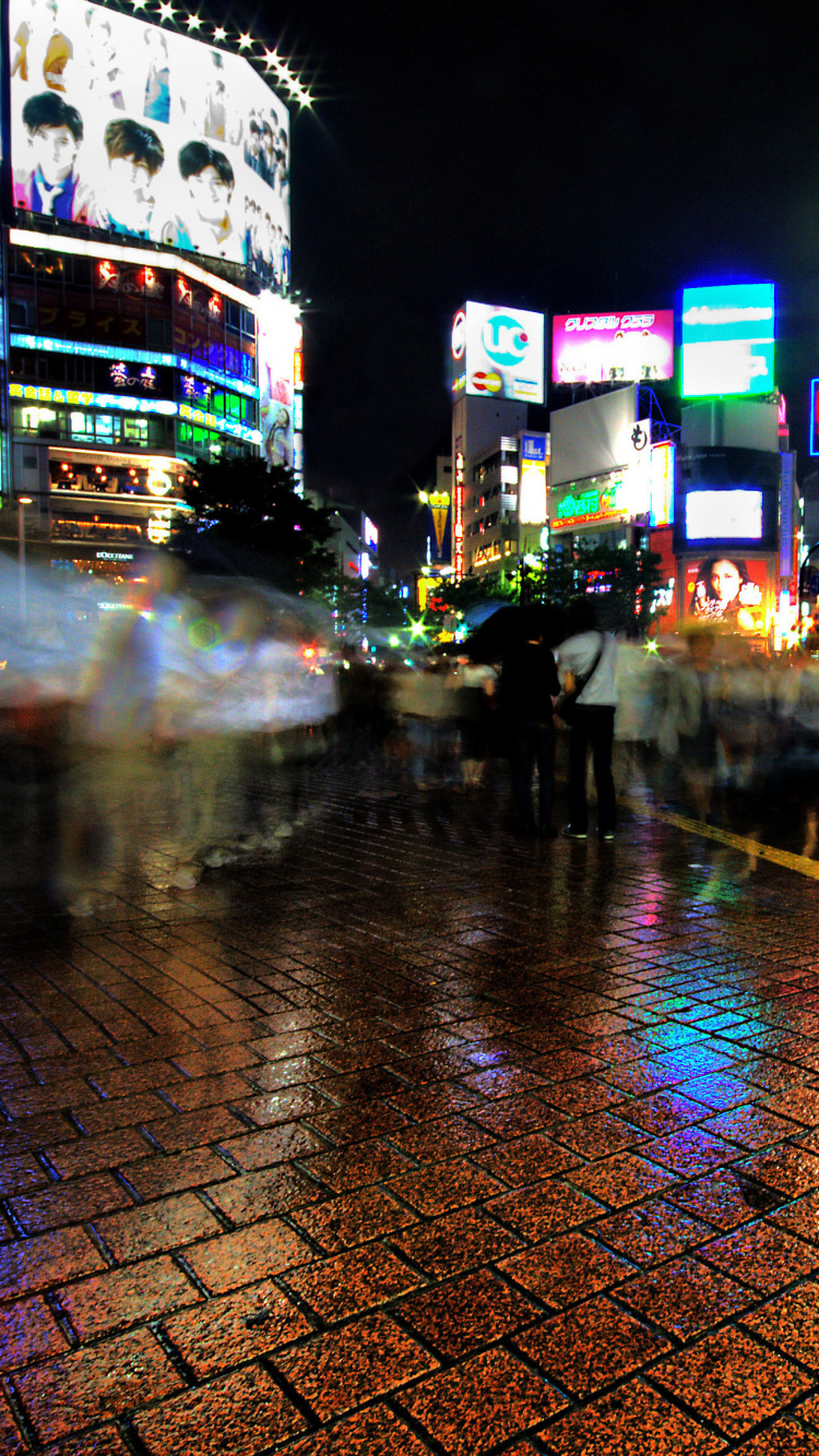 Gente Caminando en la Acera Durante la Noche. Wallpaper in 750x1334 Resolution