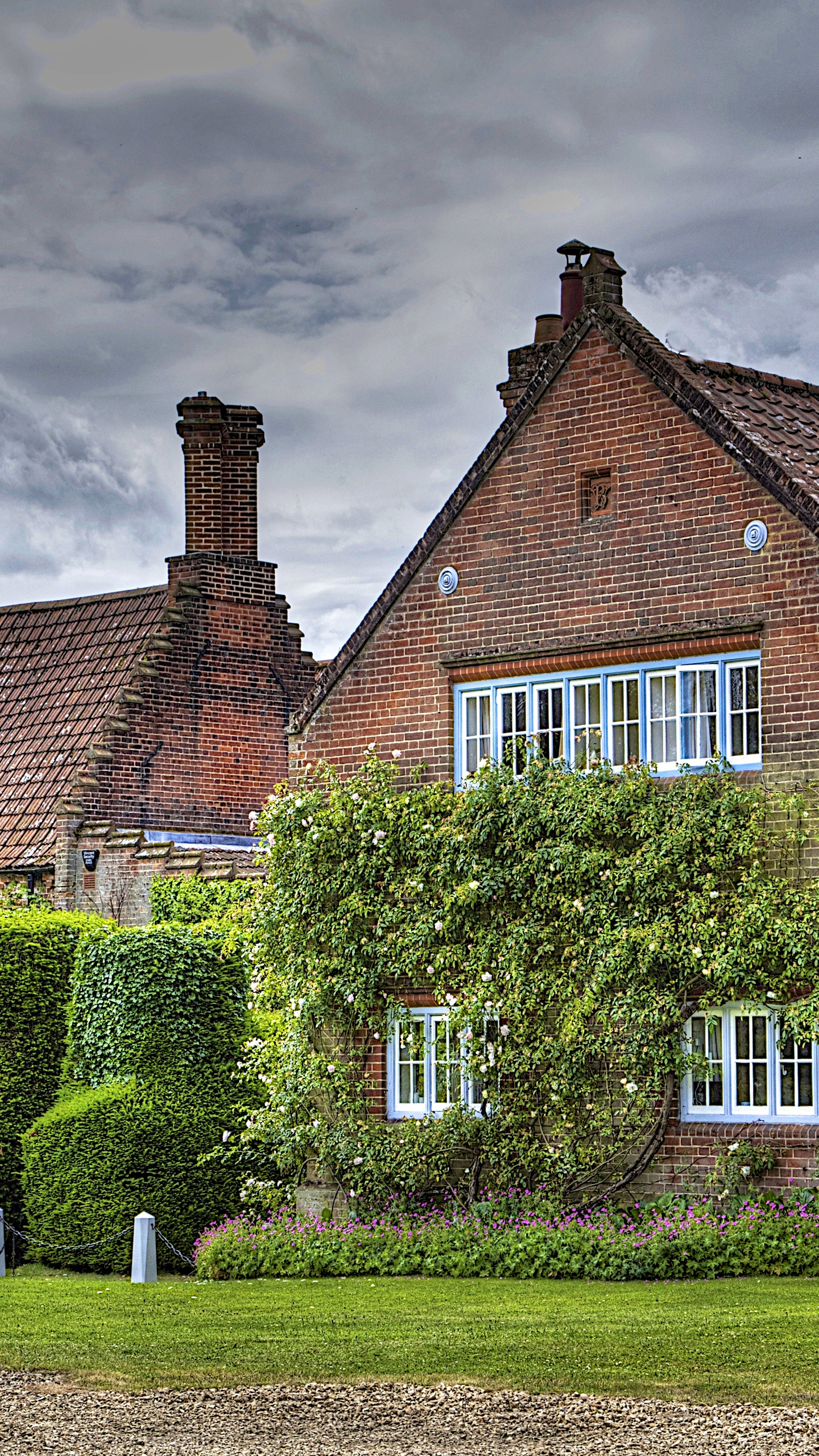 Brown Brick House With Green Grass Lawn and Trees Under Gray Clouds. Wallpaper in 1440x2560 Resolution