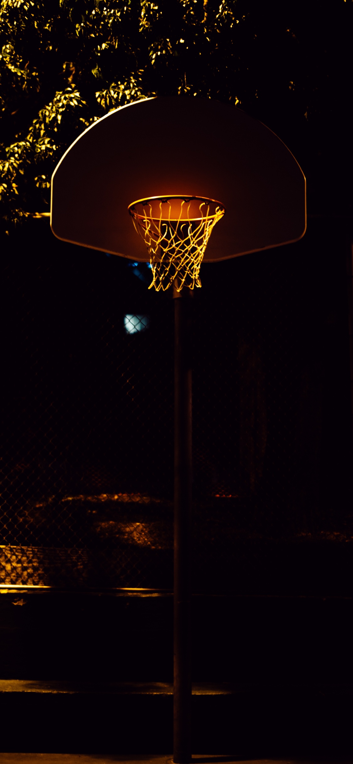 Basketballkorb Mit Nachts Eingeschaltetem Licht. Wallpaper in 1125x2436 Resolution