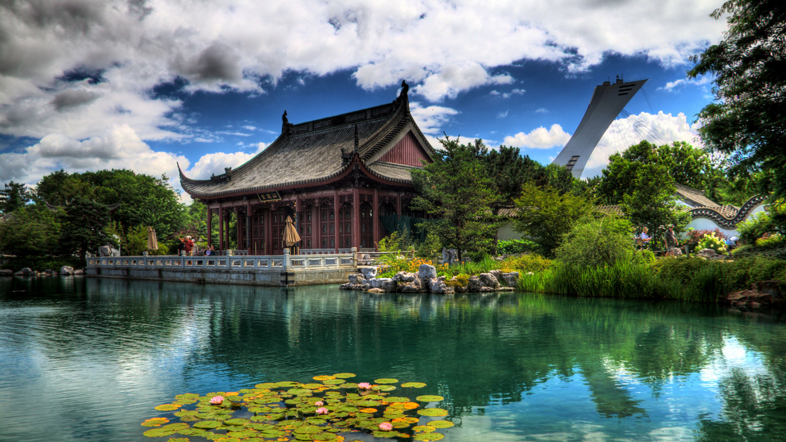 Brown and White House Near Green Trees and Lake Under Blue Sky and White Clouds During. Wallpaper in 2560x1440 Resolution