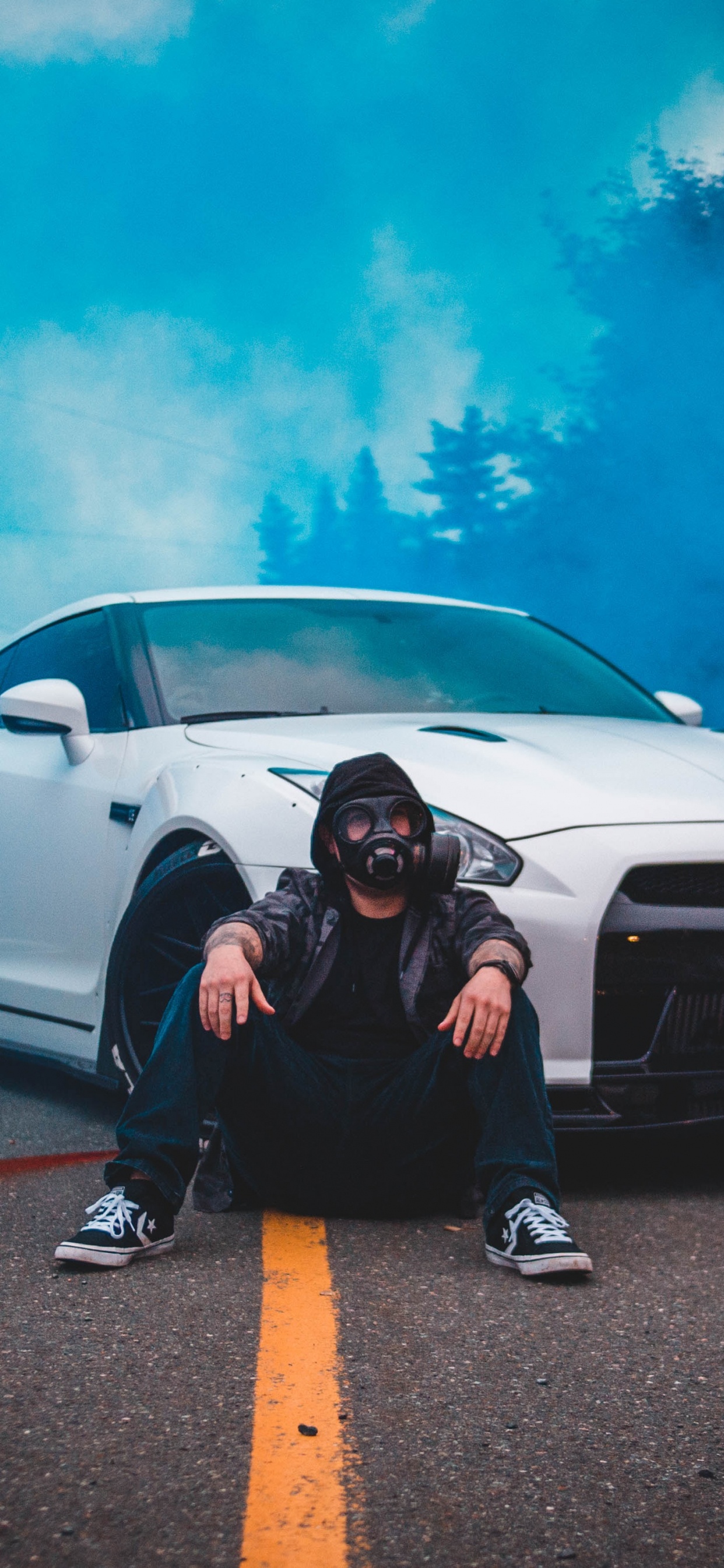Man in Black Jacket Sitting Beside White Car. Wallpaper in 1242x2688 Resolution